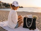 Frau am Strand mit schwarzer Smile Everyday Canvas Strandtasche.
